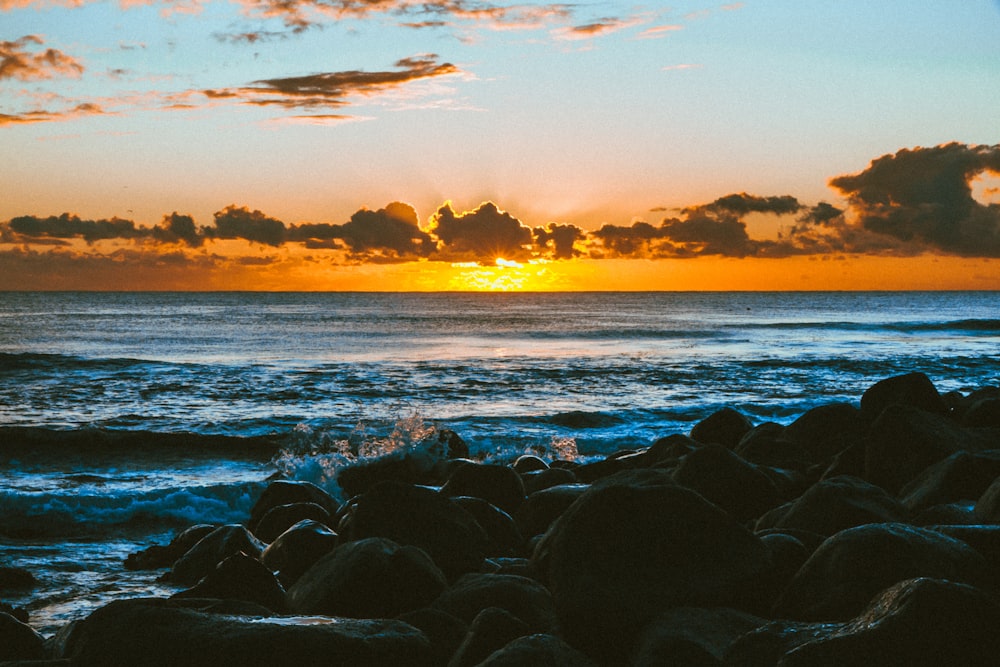 roches noires sur le bord de la mer au coucher du soleil