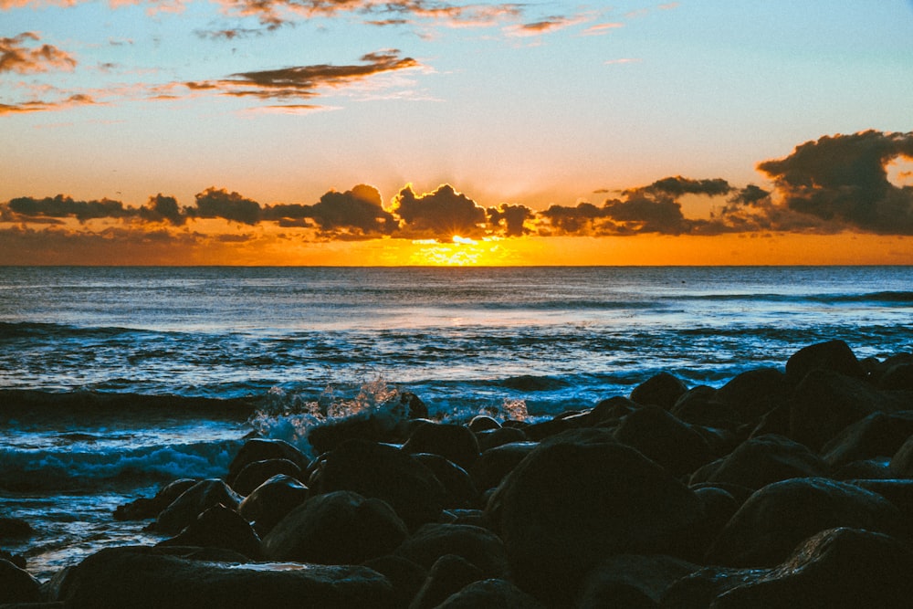 rocce nere sulla riva del mare durante il tramonto