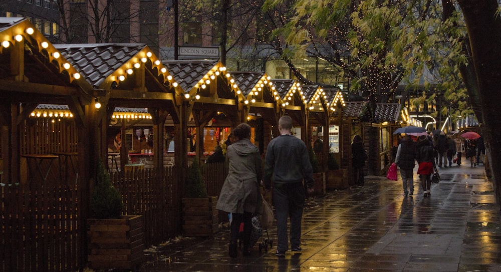 people walking on sidewalk near brown wooden building during night time