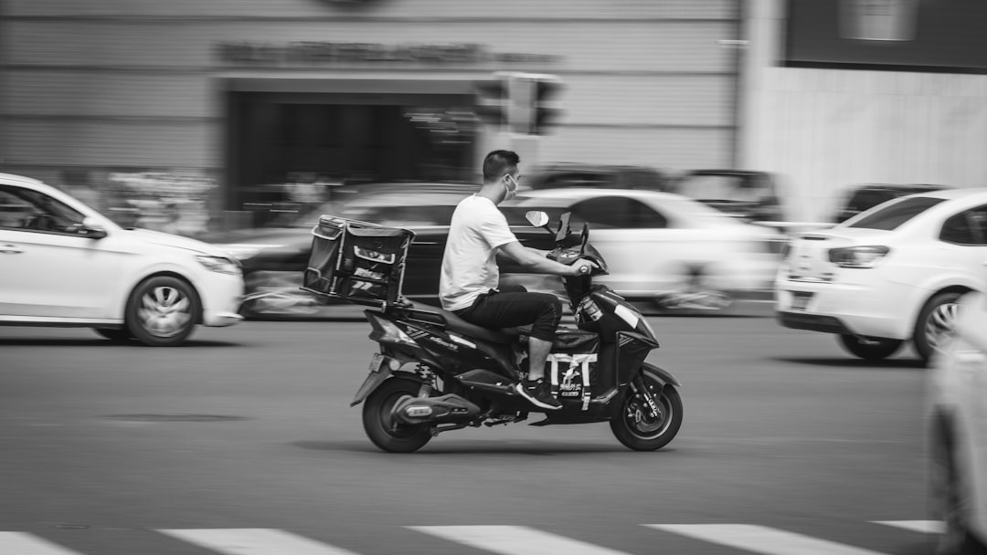 man in white shirt riding motorcycle in grayscale photography