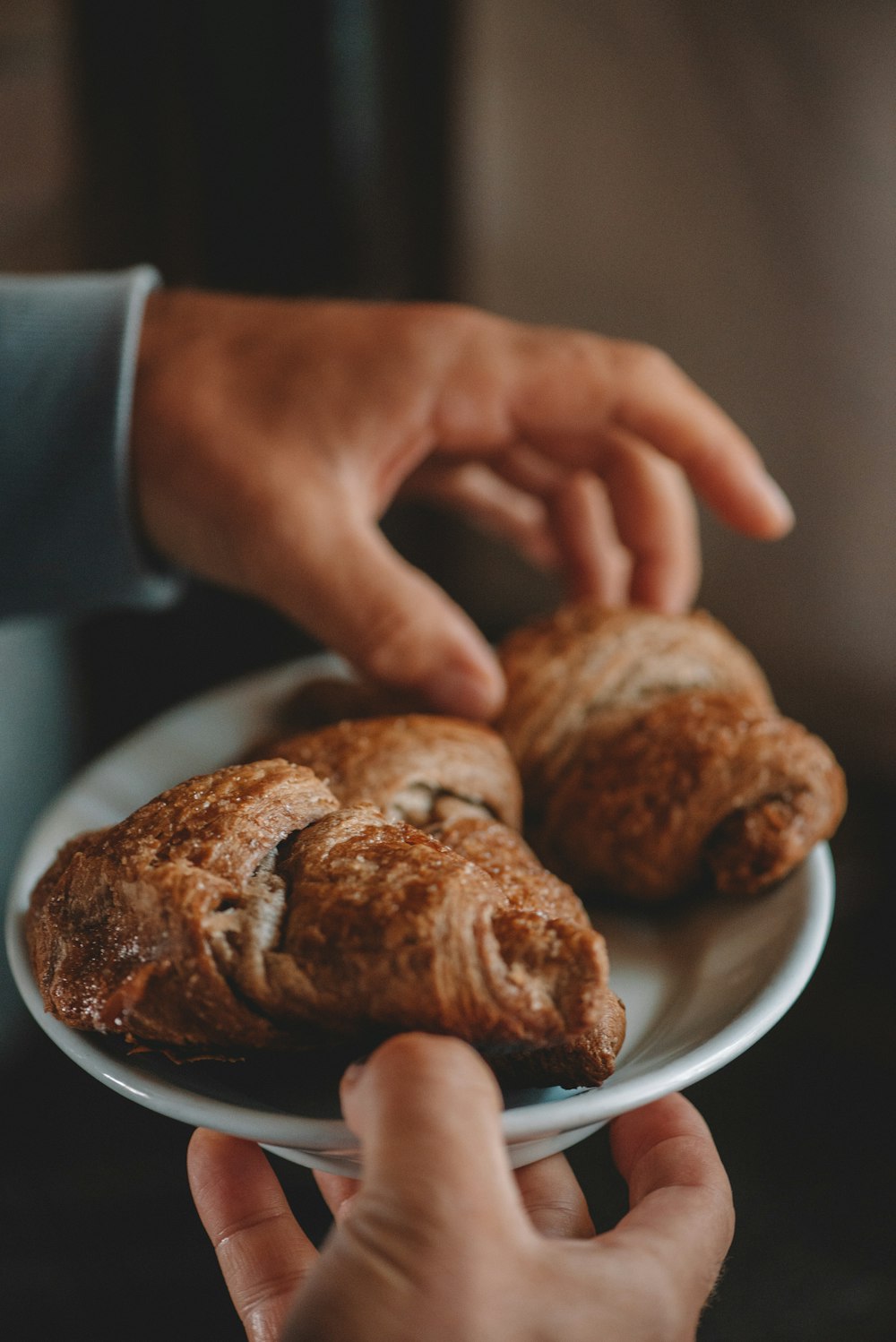 person holding white ceramic plate with brown bread