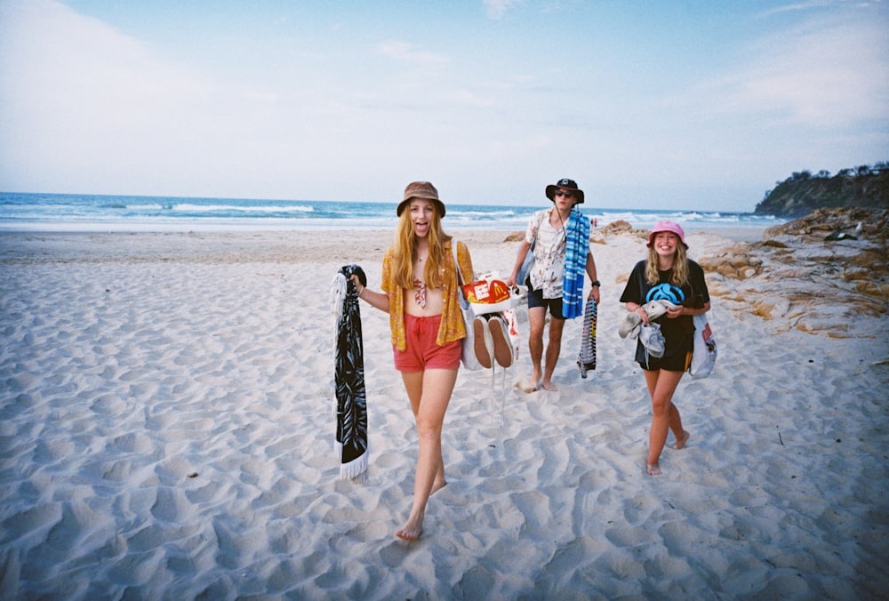 3 women standing on beach during daytime