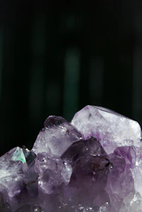 Close-up of a deep purple amethyst cluster glowing softly against an off-white background.