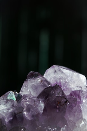Close-up of a deep purple amethyst crystal glowing softly under gentle light.