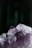 An up-close view of a cluster of amethyst crystals with a rich purple hue, showcasing their natural, jagged edges and translucent quality set against a dark background.