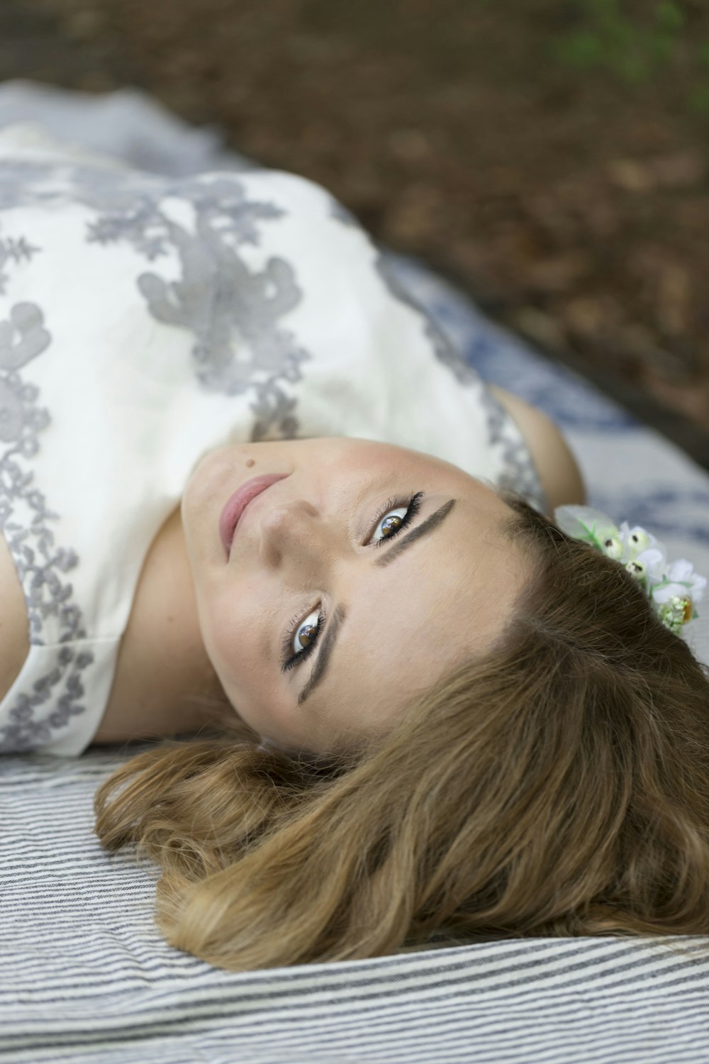 woman in white and black floral tank top lying on bed