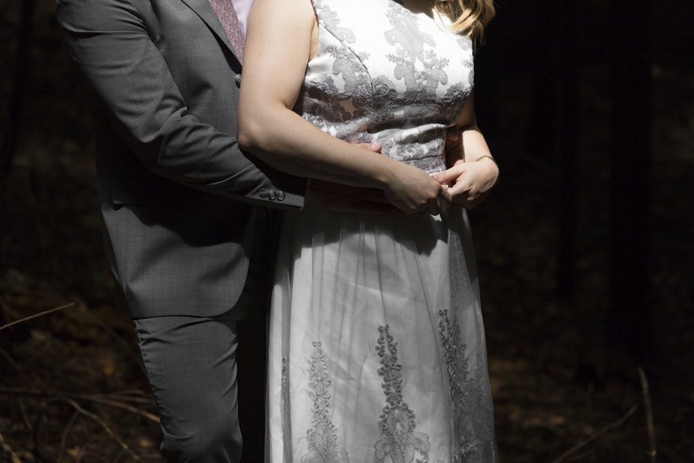 man in black suit jacket beside woman in white floral dress