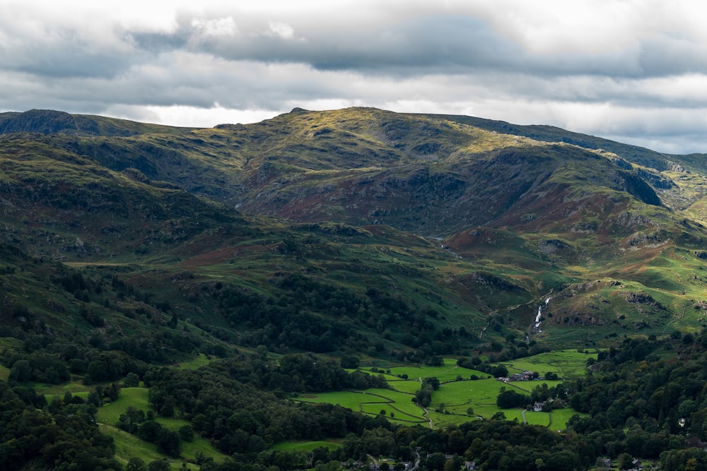 green grass field and mountain under white clouds during daytime