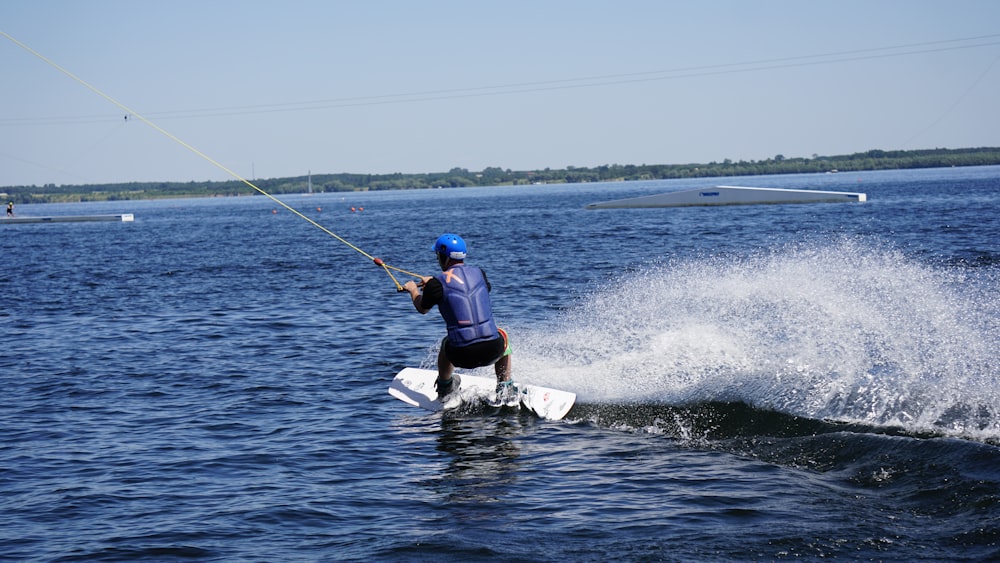 man in blue and white wet suit riding white surfboard during daytime