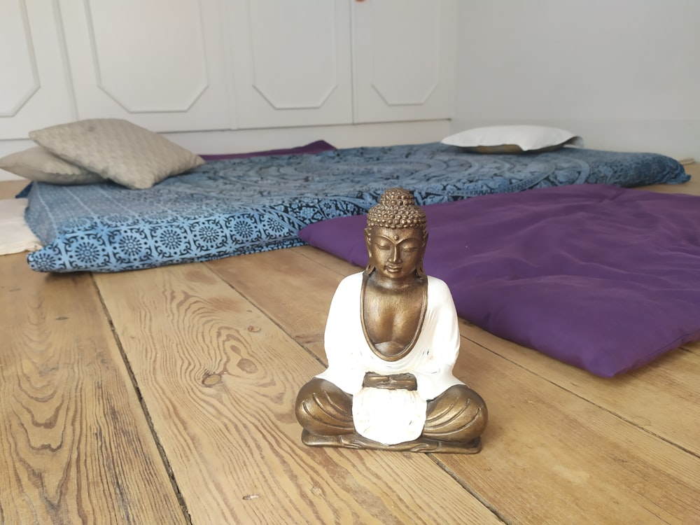weiße Keramik-Buddha-Figur auf braunem Holztisch