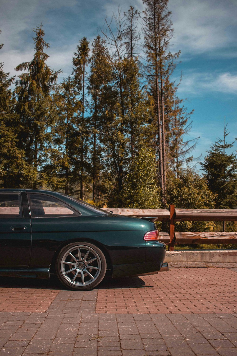 black sedan parked near brown wooden fence during daytime