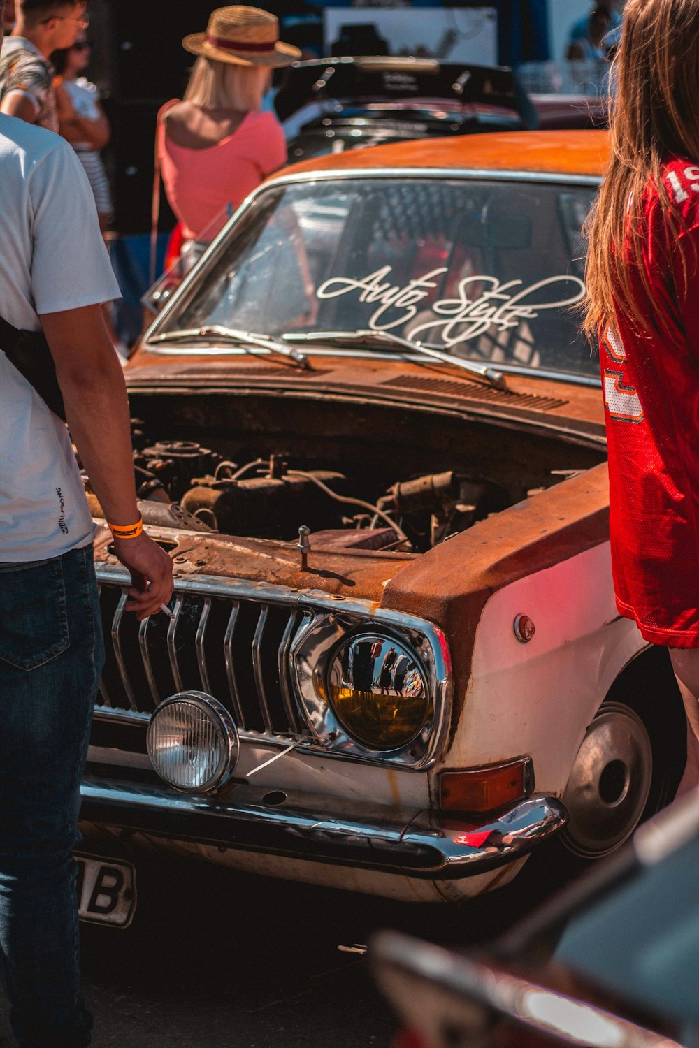 mulher na camisa vermelha que está ao lado do carro marrom