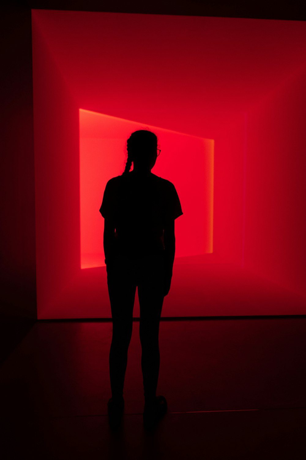silhouette de femme debout devant le mur rouge