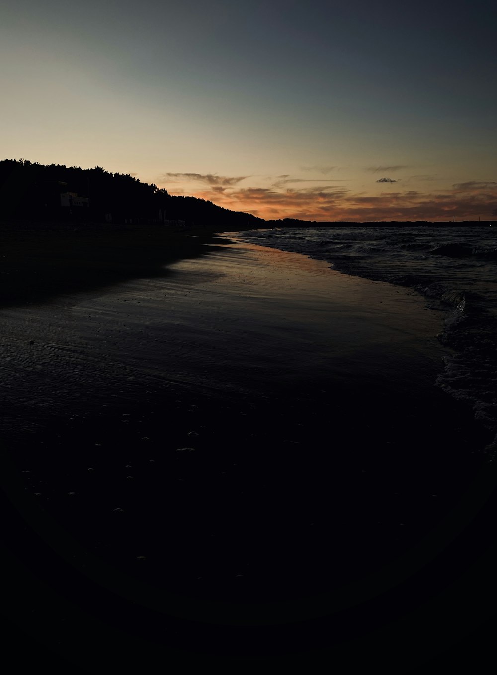 silhouette of mountain near body of water during sunset