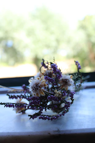 A delicate bouquet of wildflowers resting on a soft, cream-colored blanket outdoors.
