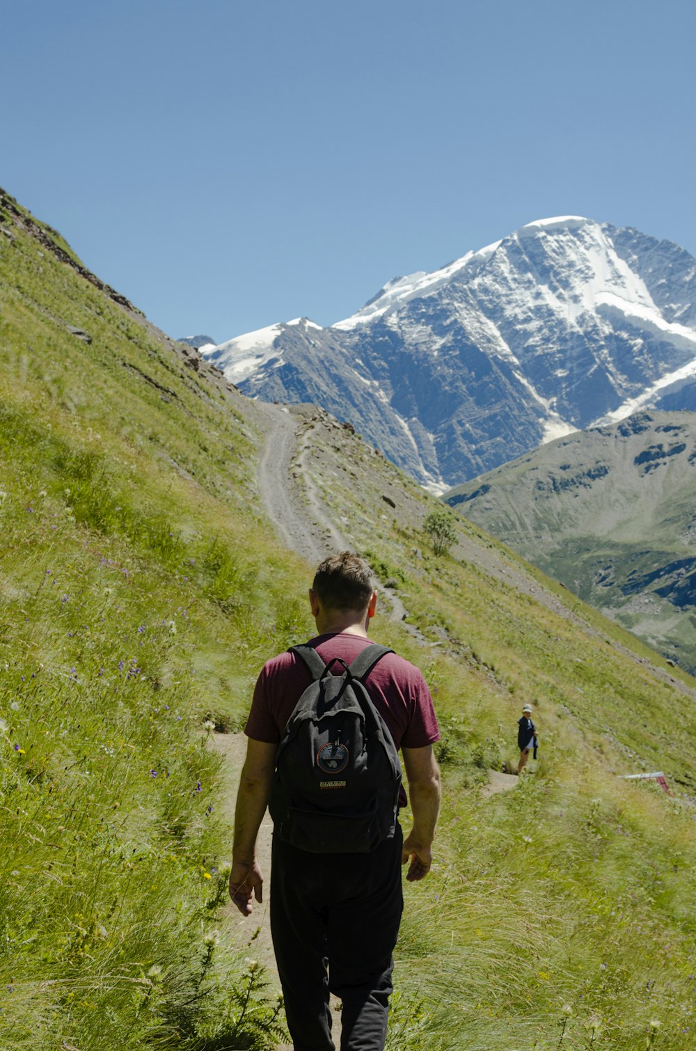 man in black t-shirt and brown shorts with black backpack walking on green grass field