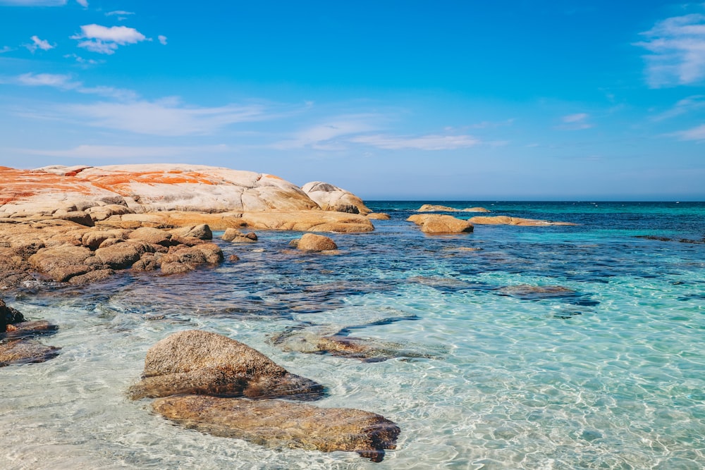 Braune Felsformation auf blauem Meer unter blauem Himmel tagsüber