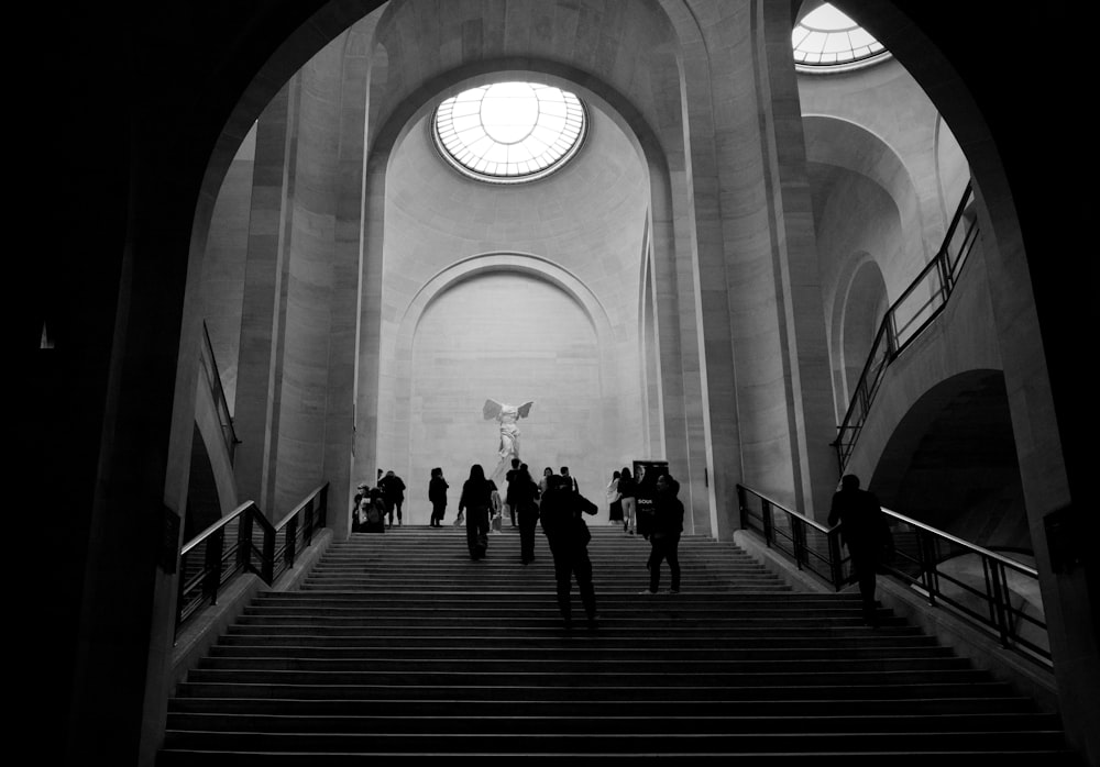 grayscale photo of people walking on stairs