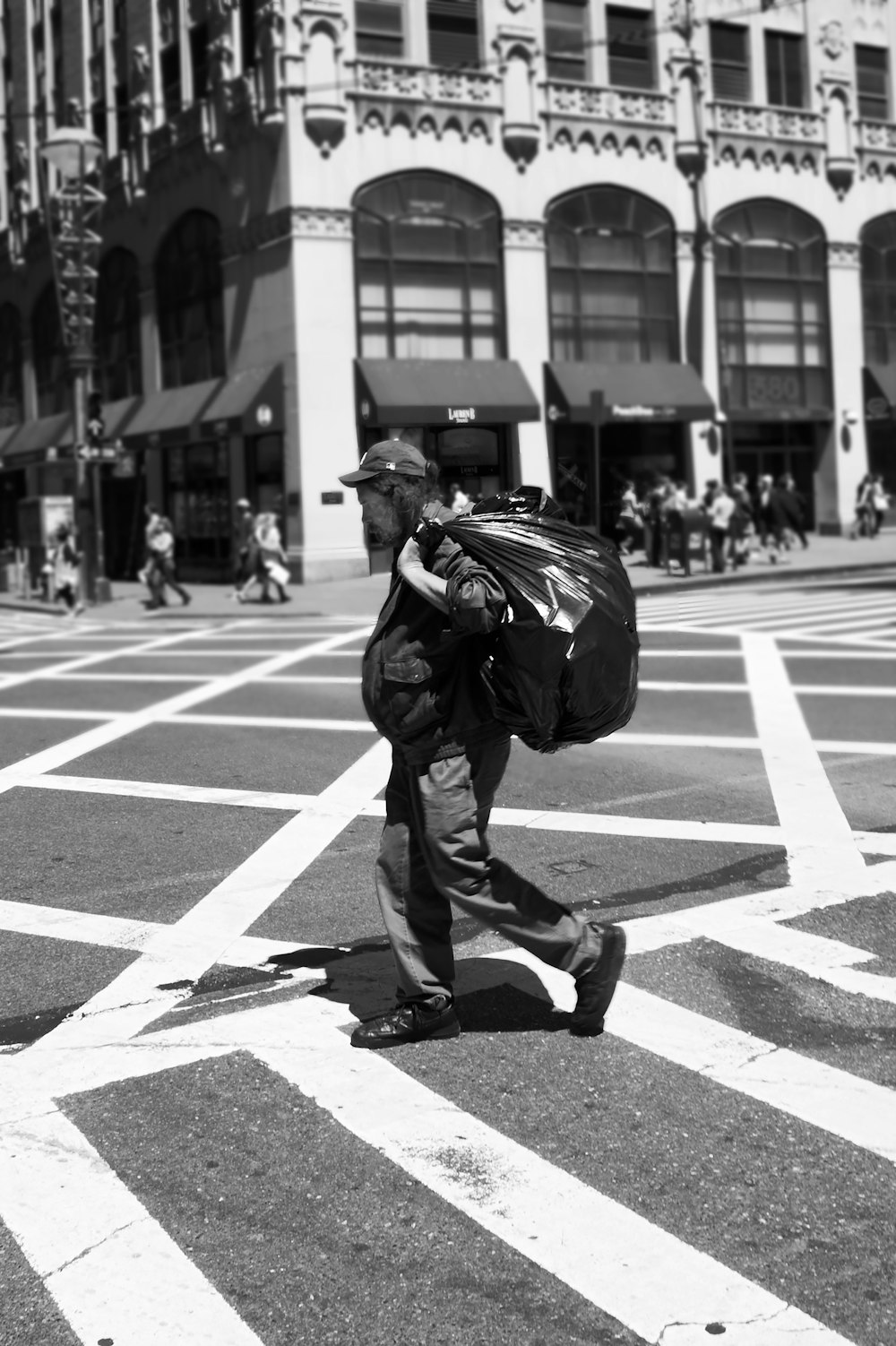 man in black jacket and pants walking on pedestrian lane in grayscale photography