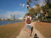 A happy customer wearing a Shine Republic backpack while walking through a city park.