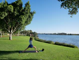 A peaceful yoga session outdoors surrounded by light blue sky and greenery.