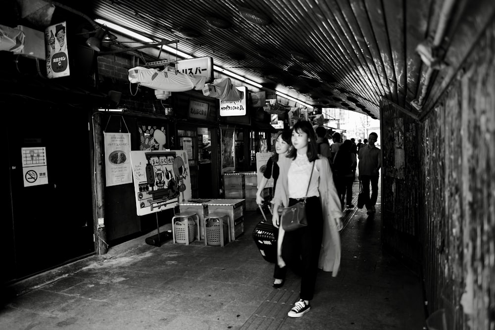 grayscale photo of man in white dress shirt and black pants standing near store