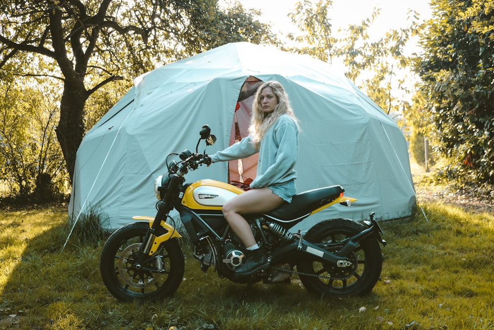 woman in white tank top riding on black and yellow motorcycle