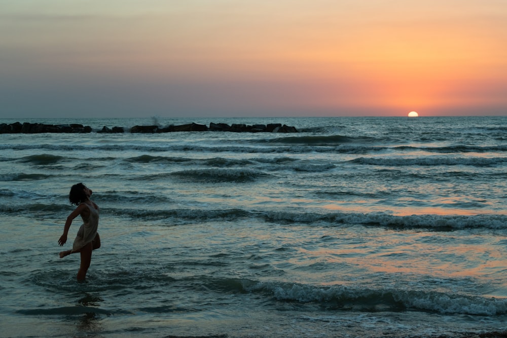 person in white shirt standing on seashore during daytime