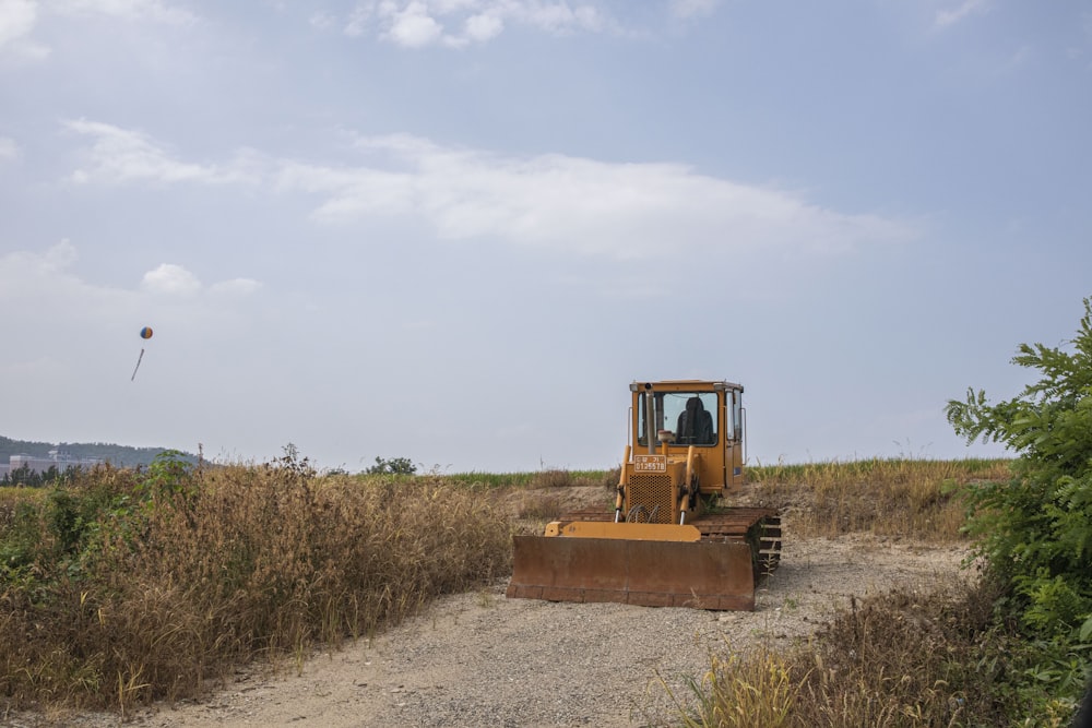 yellow and black heavy equipment on brown field under white clouds during daytime