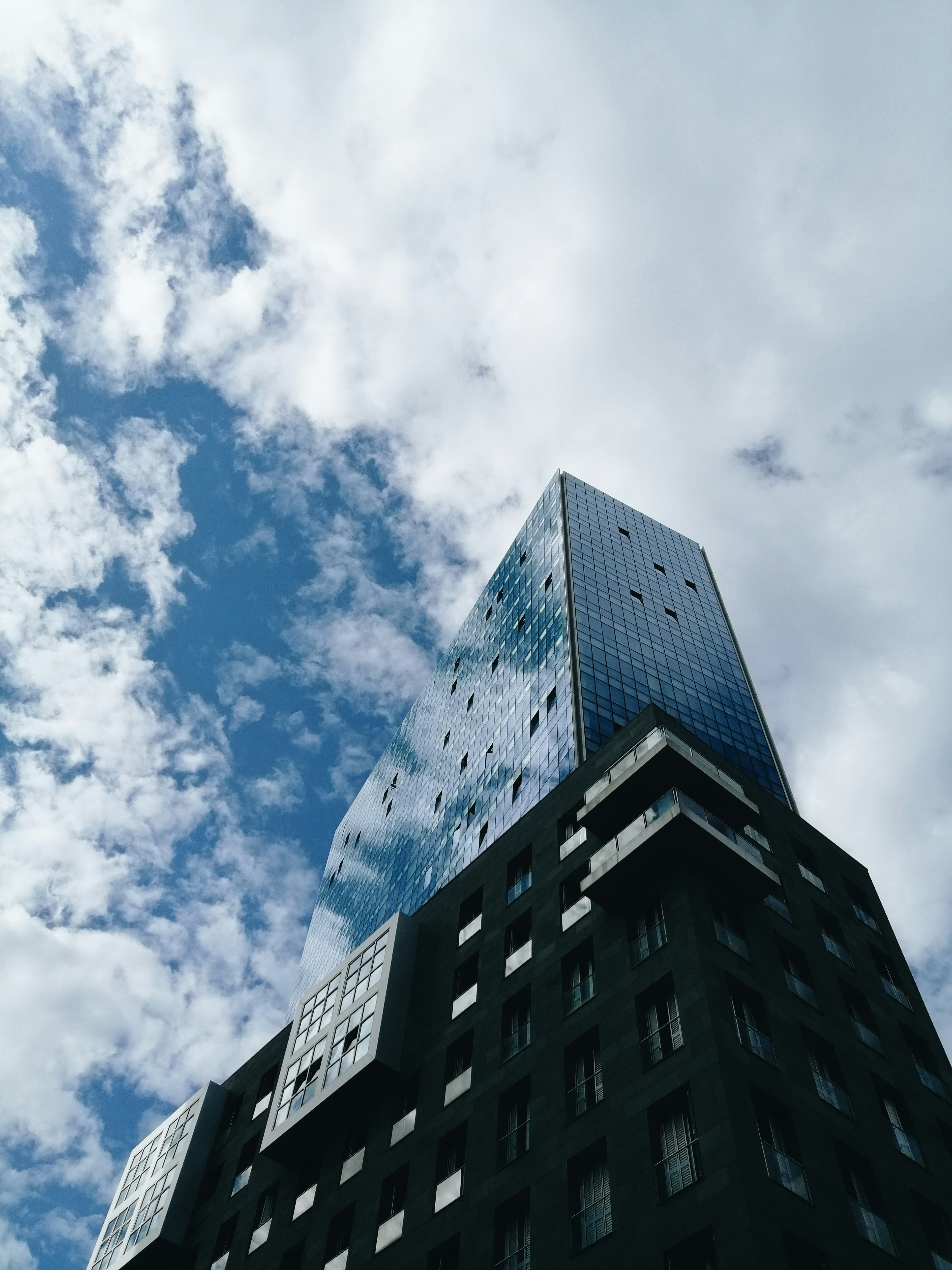 low angle photography of high rise building under blue sky and white clouds during daytime