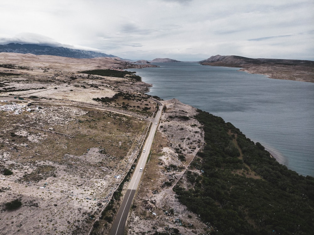 Route en béton gris près d’un plan d’eau pendant la journée