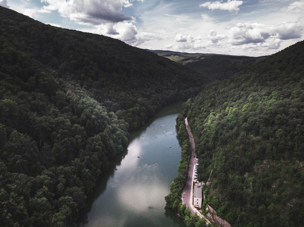 green mountains and river under white clouds and blue sky during daytime