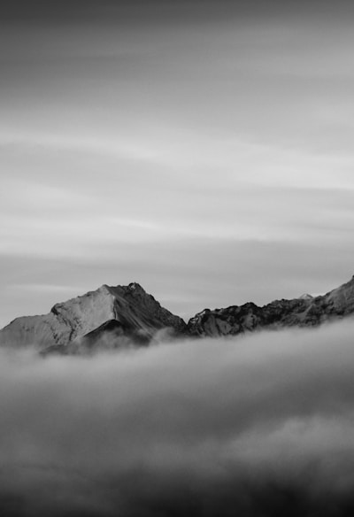 grayscale photo of mountains under cloudy sky