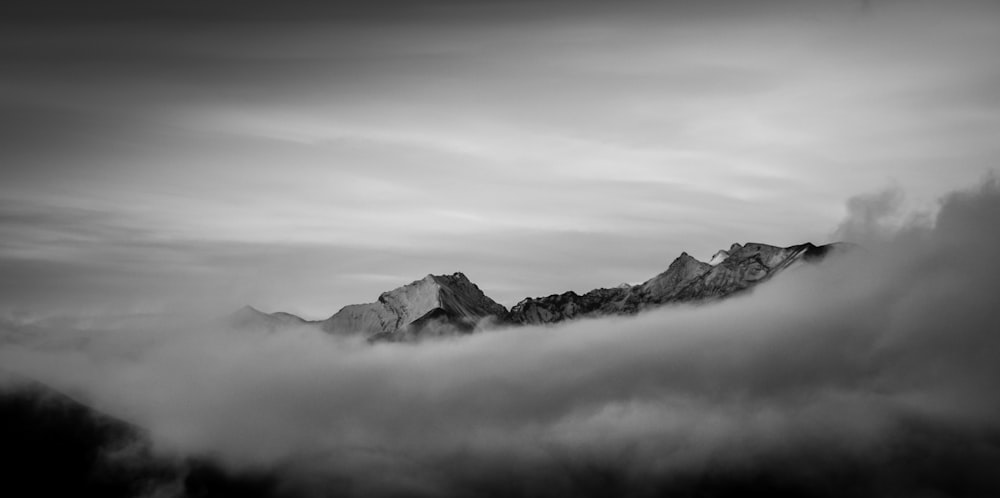 grayscale photo of mountains under cloudy sky