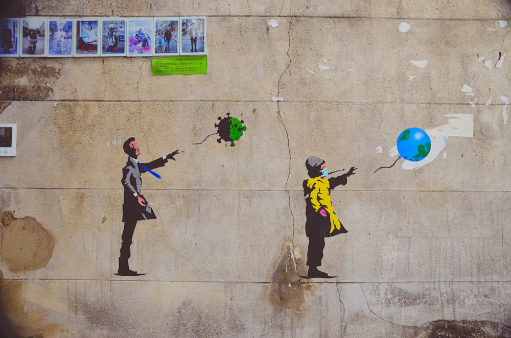 man in black and yellow jacket and black pants holding green and blue balloons