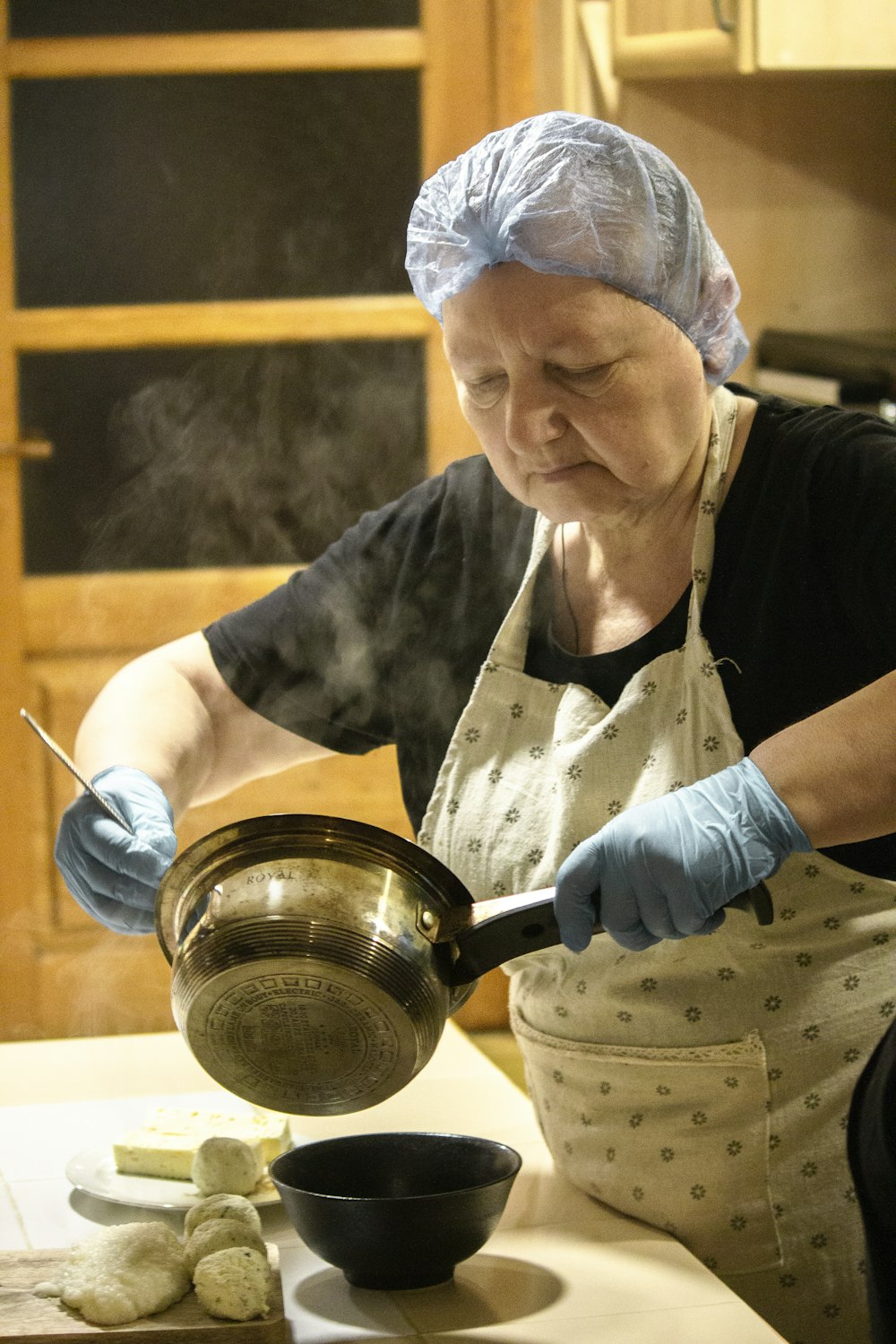 woman in black and white shirt holding stainless steel pot