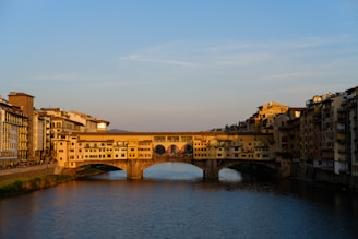 A vibrant panoramic view of the ancient Roman bridge over the Guadiana River in Mérida, Extremadura, during golden hour.