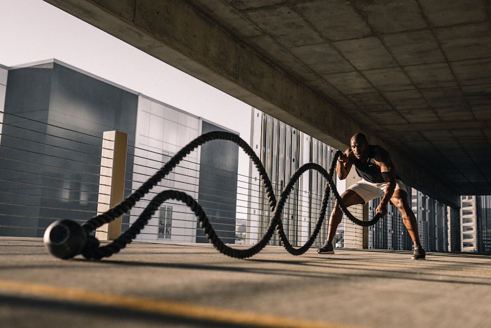 Man intensely doing battle ropes during an outdoor workout, symbolizing the need for rapid rehydration