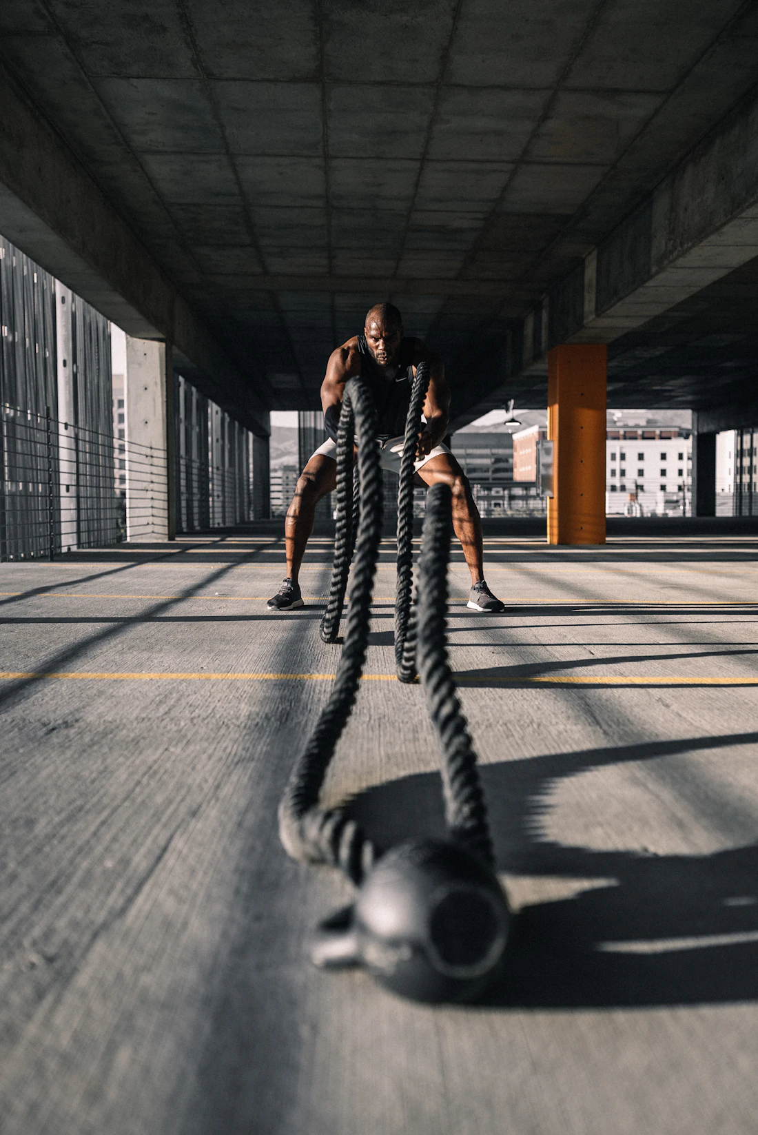 Atleta trabajando con cuerdas de batalla y kettlebell sobre piso de concreto
