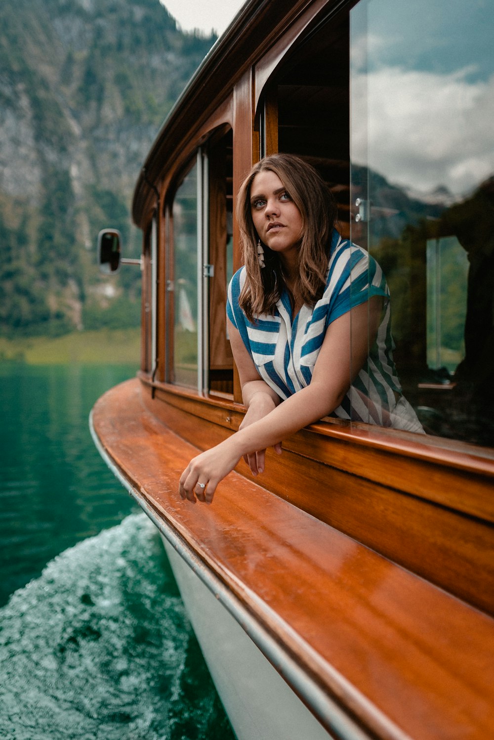 mulher na camisa da listra azul e branca sentada no barco de madeira marrom