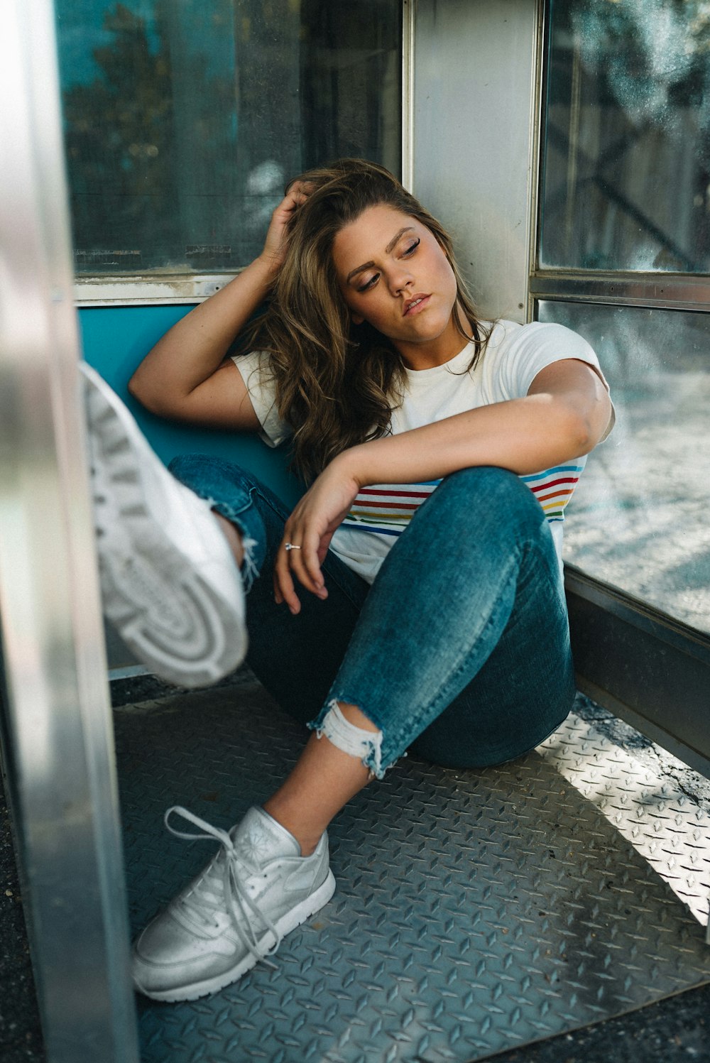 Mujer con camiseta blanca y jeans de mezclilla azul sentada en el asiento del tren