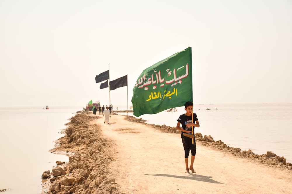 man in black shirt and black shorts walking on beach shore during daytime