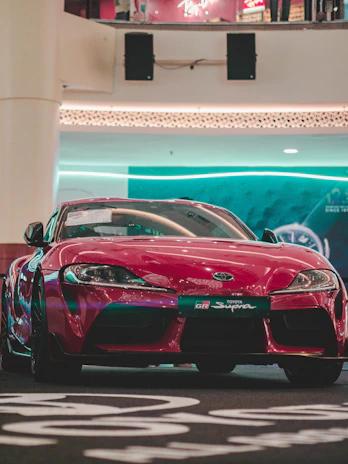 A sleek red sports car gleaming under the showroom lights.