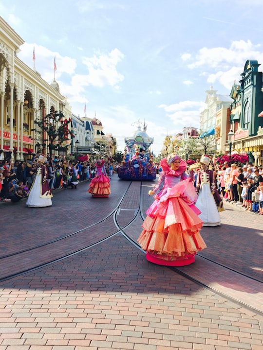 woman in pink dress walking on street during daytime in Disneyland Park, Sleeping Beauty's Castle France