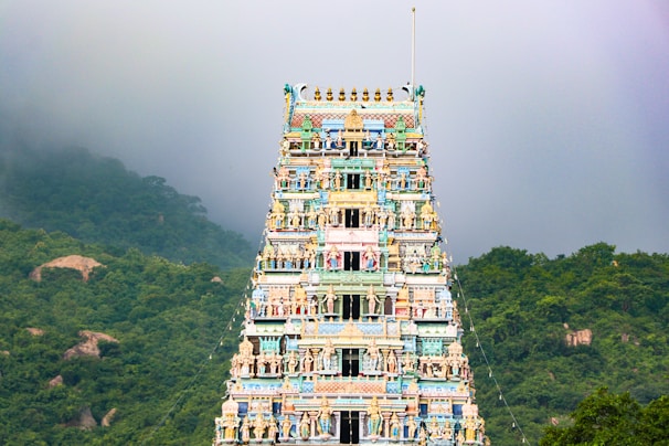 Maruthamalai Temple perched on a lush green hill with devotees climbing the steps.