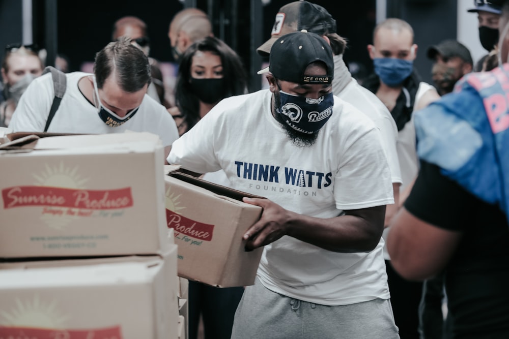 man in white crew neck t-shirt holding white box