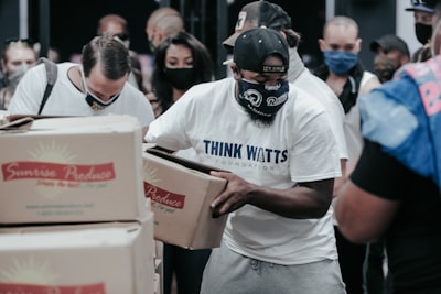 man in white crew neck t-shirt holding white box rams teams background