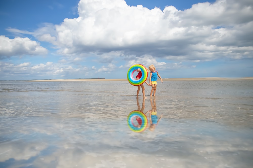 girl in white dress holding green and yellow bicycle on beach during daytime