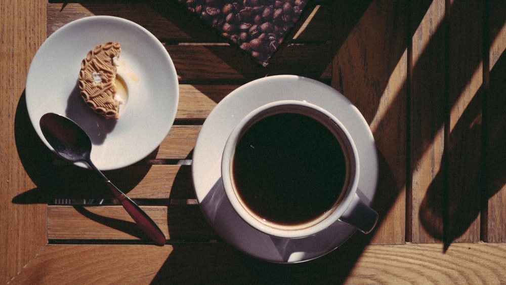 weiße Keramiktasse mit Untertasse auf braunem Holztisch