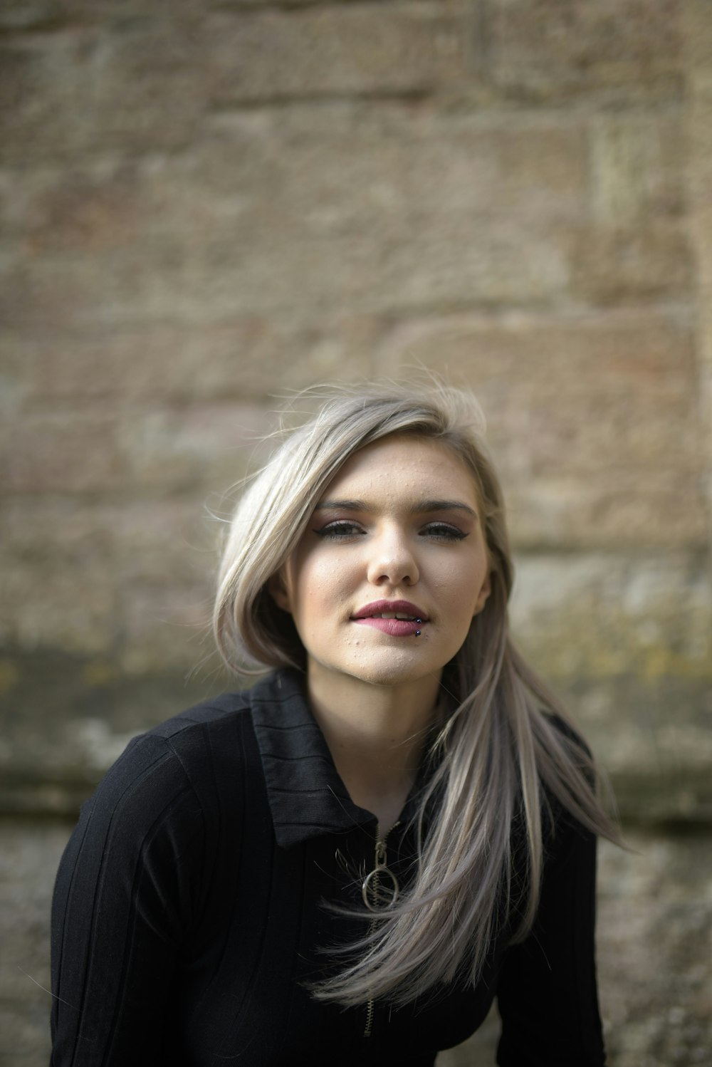 woman in black shirt standing near brown wall